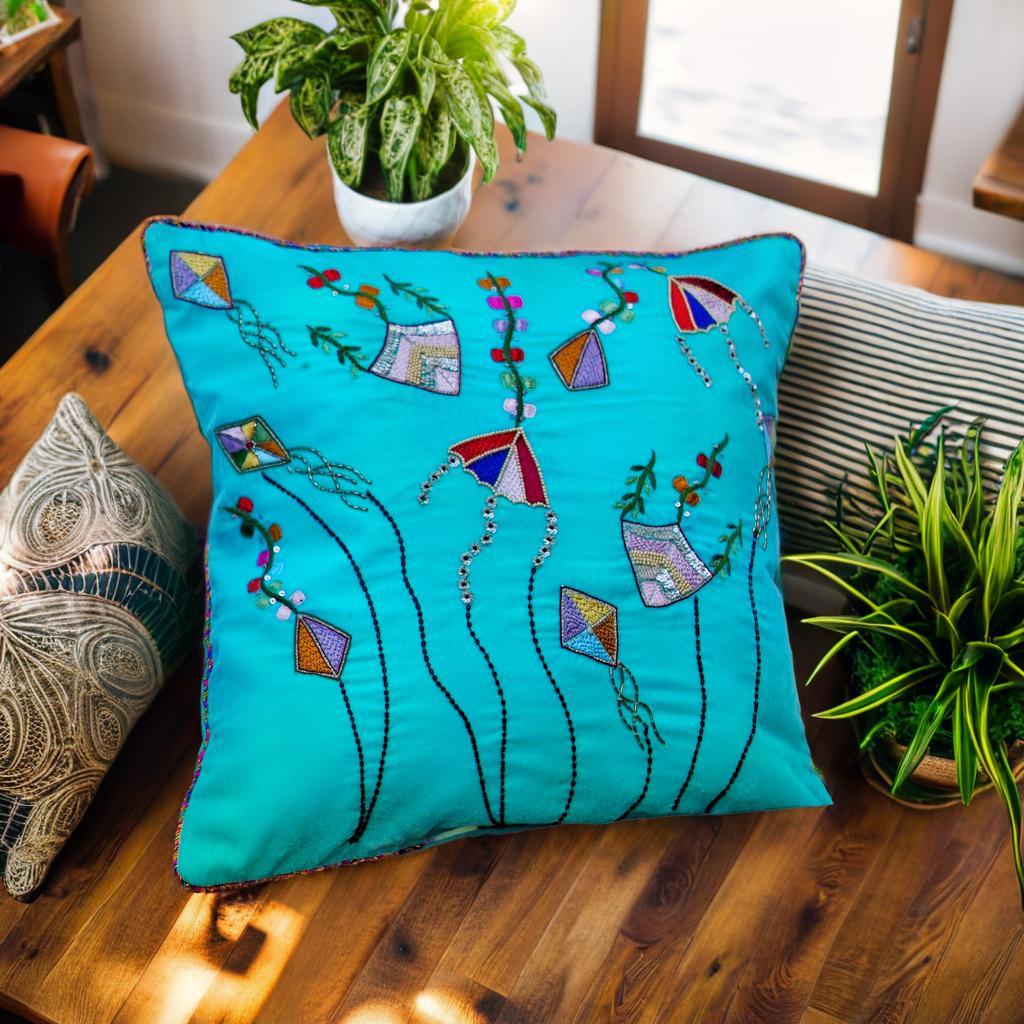 Detailed view of exquisite Zardozi embroidery on a sky blue cushion cover, capturing the essence of the Patangbazi kite flying theme with colorful motifs
